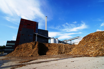 bio power plant with storage of wooden fuel against blue sky