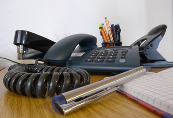 Telefon, Locher, Kugelschreiber auf dem Schreibtisch im Büro