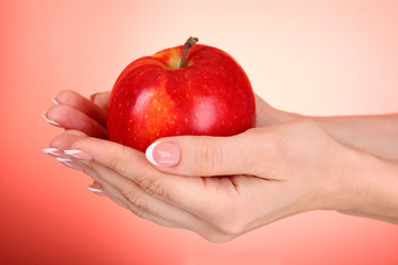 An apple on the hand on red background