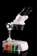 Laboratory metal microscope and test tubes with liquid  on the b
