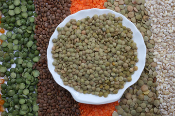 Ceramic plate with lentils over seeds and grains background