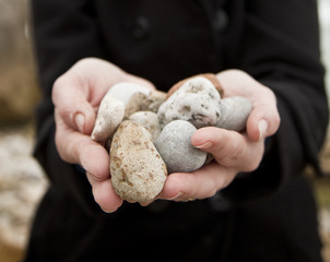 Woman holding pebbles out to camera.