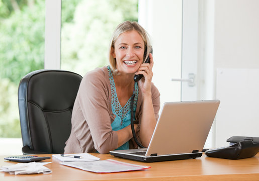 Woman working on her computer while she is phoning