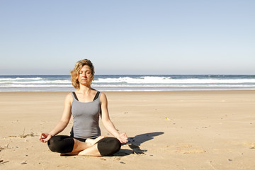 Fototapeta na wymiar Young healthy woman meditating at the beach