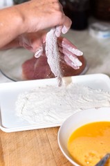Fresh meat with flour on in the hands of a cook with blurry back