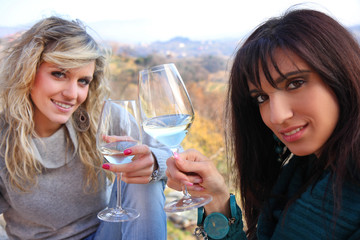 ragazze brindano all'aperto con vino bianco