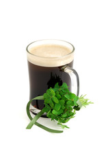 Dark beer in glass and bouquet of false shamrock with green ribb