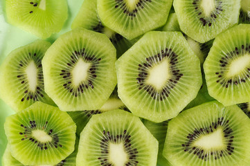 Fresh kiwifruit slices on the green plate.