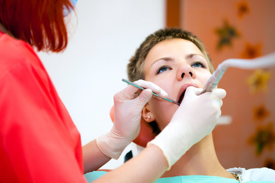 Image of young lady with dentist over her checking oral cavity .