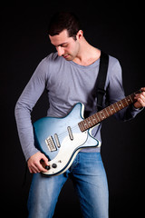 Obraz premium Young man playing guitar isolated on black
