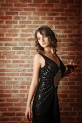 The beautiful girl in an evening dress with a red wine glass