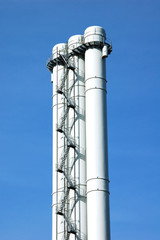 Chimney in an industrial area on blue sky background