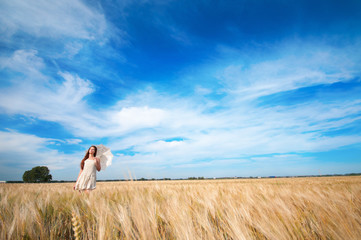 Woman with umbrella walking in field.