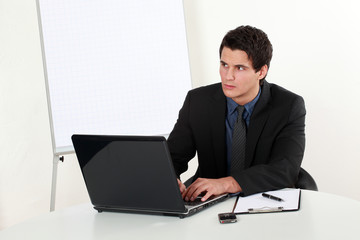 Junger Mann erfolgreich besorgt am Laptop