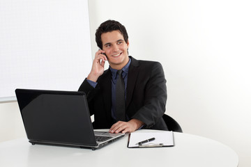 Junger Mann mit Handy am Laptop