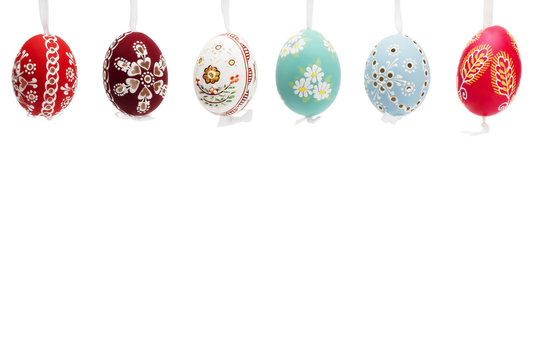 reihe h&auml;ngender handbemalter ostereier vor weissem hintergrund