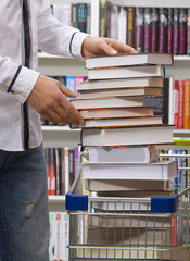 Closeup of hands putting books in a basket for purchases