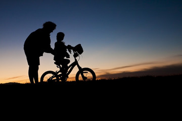 Obraz na płótnie Canvas Parent Teaching Child to Ride a Bike