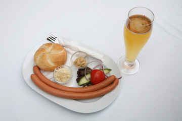 Vienna sausages with bread, salad and beer on a white background