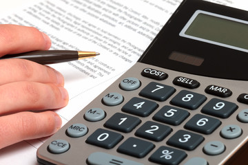 Businessman doing some paperwork with pen and calculator