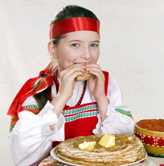 Russian  girl  behind a table with pancakes