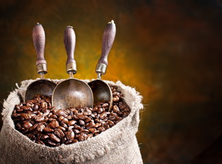 Sack of coffee beans and scoop. On a dark background.