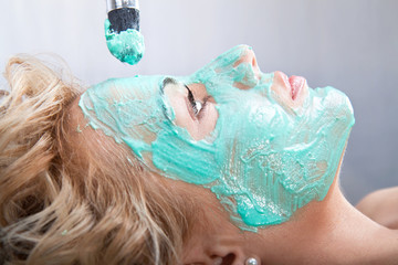 Applying mud face pack on woman face