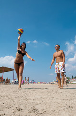 young people playing volleyball on the beach