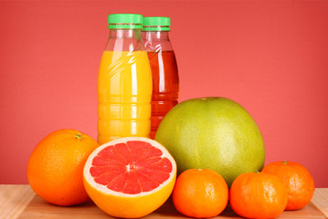 bottles of juice  with ripe fruits on yellow background