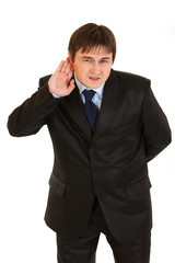 Concentrated businessman holding hand at ear and listening