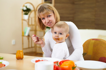 mother feeding her little son at home