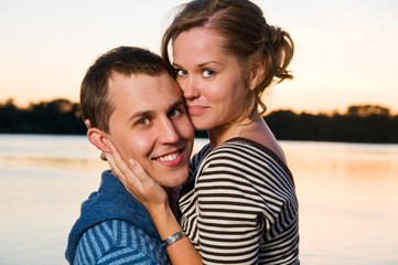 young attractive couple near lake at sunset