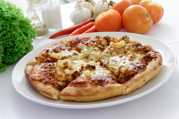 Pizza on a plate with some ingredients in the background
