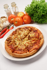 Pizza on a plate with some ingredients in the background