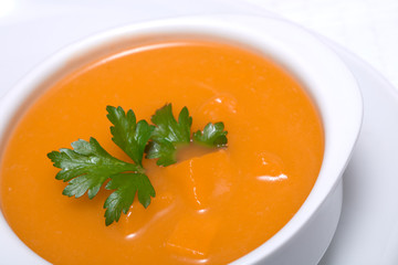 Pumpkin soup in white bowl  with parsley