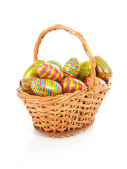 Cane basket with colorful easter eggs over white background