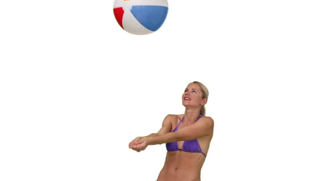 Pretty lady in purple swimsuit playing with a beach ball