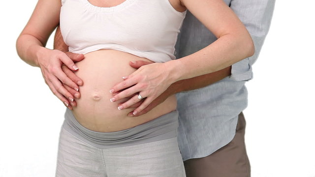 Man touching belly of his wife to feel their future baby moving