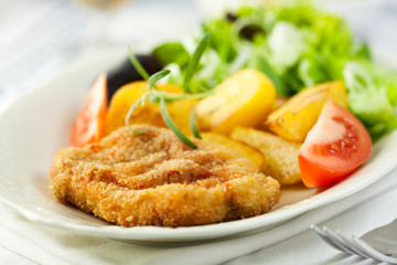Delicious schnitzel with baked potatoes and salad