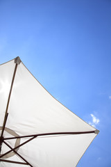 white linen umbrella in front of a deep blue sky