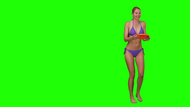 Pretty woman in purple swimsuit playing with a frisby