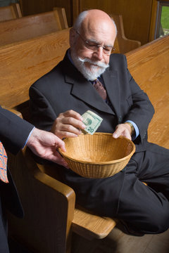Senior Man Putting Money into Church Basket