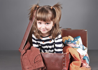 four-year girl joyfully sits in an old suitcase