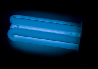 Energy saving lamp (lightbulb) with dark blue colour on the blac