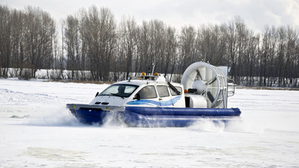 Hovercraft rides on the frozen river, picking up snow dust.