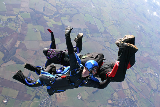 Four skydivers jump from an airplane