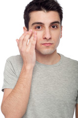 Young man applying eye cream