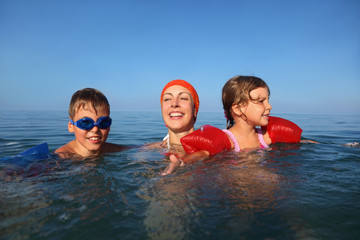 Mother in summer teaches to swim two children boy and girl