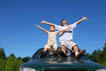Father with  son sit on  roof of car, lift  person in sky