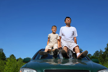 Father with  son sit on  roof of car in  day-time